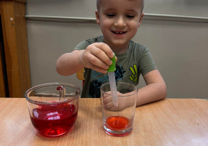 Tymek przelewa kolorową wodę przy pomocy pipety