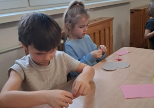 Chłopiec wykleja wydzieranką serduszko.