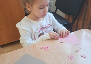 Dziewczynka wykleja wydzieranką serduszko.