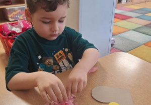 Chłopiec wykleja wydzieranką serduszko.