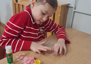 Dziewczynka wykleja wydzieranką serduszko.