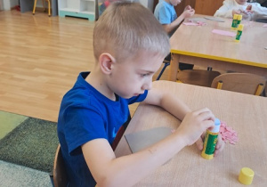 Chłopiec wykleja wydzieranką serduszko.