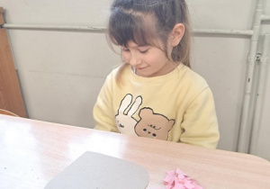 Dziewczynka wykleja wydzieranką serduszko.