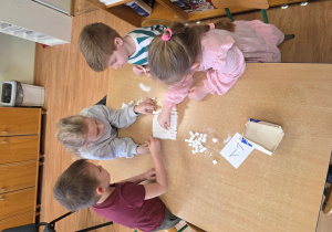 Gabryś, Klara, Laura i Antek budują piramidę z kostek cukru.