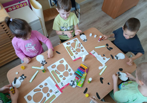 Dzieci wykonują z gotowych elementów pandę.