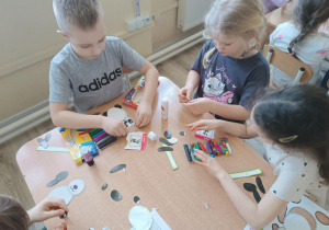 Dzieci wykonują z gotowych elementów pandę.