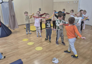 Dzieci stoją w rzędzie trzymając szarfy przed sobą.