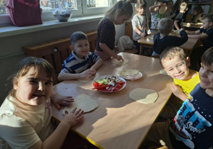 dzieci dekorują swoja pizze