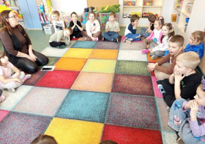 Dzieci siedzą na dywanie.