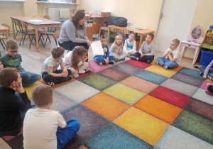 Dzieci siedzą na dywanie.