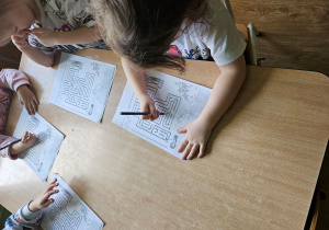 Dziewczynka prowadzi ołówek w labiryncie.