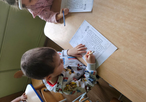 Chłopiec prowadzi ołówek w labiryncie.