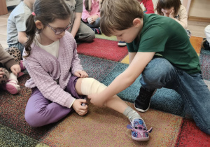 Dzieci ćwiczą w jaki sposób opatruje się drobne rany.