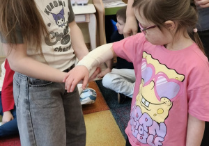 Dziewczynki ćwiczą w jaki sposób opatruje się drobne rany.