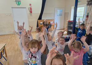 dzieci wyciągają ręce do góry