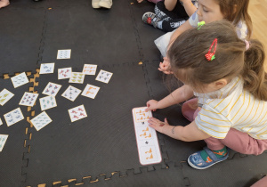 dziewczynka nakłada obrazek z odpowiednią ilością dinozaurów