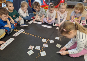 dziewczynka wybiera odpowiedni obrazek z dinozaurami