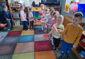 dzieci chodzą po kole trzymając serduszka