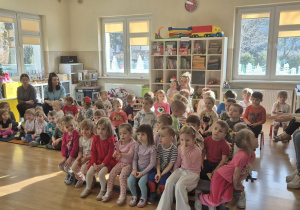 Dzieci siedzą na widowni oglądając występ