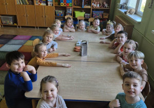 Dzieci siedzą przy stolikach w sali