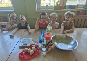 Pięcioro uśmiechniętych dzieci siedzi przy stoliku