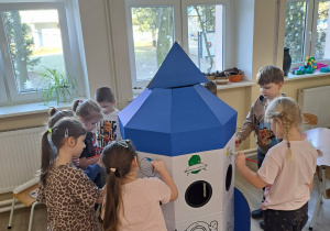 Dzieci malują farbami rakietę.