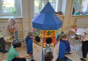 Dzieci malują farbami rakietę.