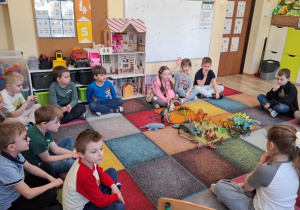 Dzieci siedzą na dywanie.