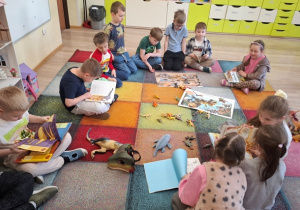 Dzieci siedzą na dywanie.