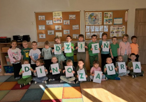 Dzieci pozują do zdjęcia z napisem dzień dinozaura.