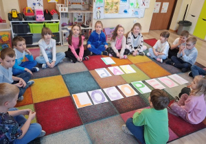 Dzieci siedzą na dywanie.