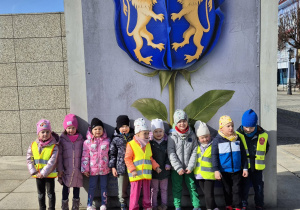 Dzieci stoją przed namalowanym herbem Kutna