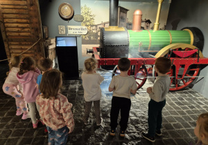Dzieci w podziemiach pałacu oglądają model lokomotywy
