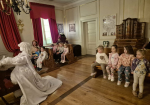 Dzieci siedzą na ławkach w muzealnej kaplicy