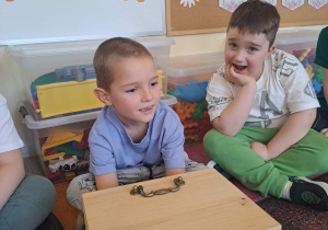 Dzieci biorą udział w zabawie sensorycznej "Damskie pudełko".