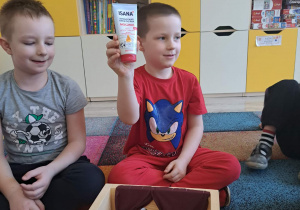 Dzieci biorą udział w zabawie sensorycznej "Damskie pudełko".