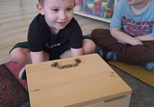 Dzieci biorą udział w zabawie sensorycznej "Damskie pudełko".