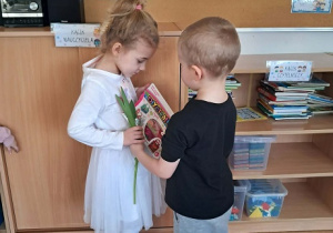 Chłopiec wręcz dziewczynce kwiatka.