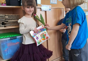 Chłopiec wręcz dziewczynce kwiatka.