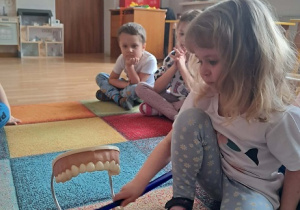 Dziewczynka prezentuje jak myć zęby.