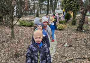 Dzieci stoją na ścieżce w przedszkolnym ogrodzie