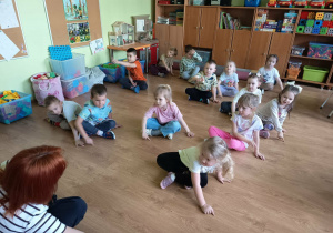 Dzieci siedzą rysując palcem na podłodze