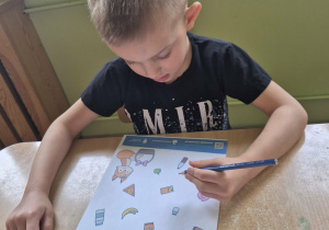 Chłopiec wypełnia kartę pracy