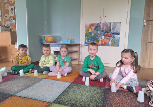 dzieci trzymają kubeczki z ukrytymi guzikami