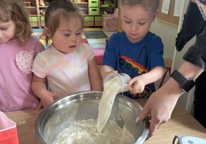 Olek wlewa do miski szklankę mleka