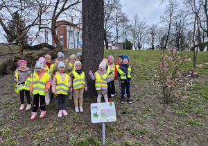 Dzieci stoją obok drzewa