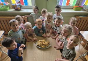 Dzieci stoją przy stoliku, przed nimi leżą upieczone rogaliki