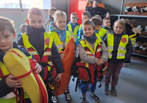 Przedszkolaki przymierzają stroje strażackie.