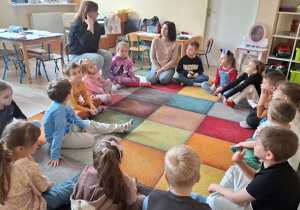 Dzieci siedzą na dywanie.
