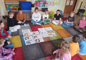 Dzieci siedzą na dywanie.